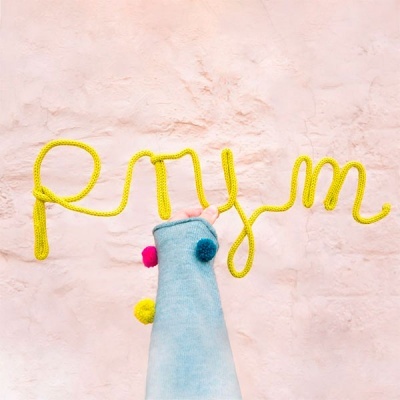 Cordão amarelo formando a palavra Rum com figura de tecido azul e pompons em fundo rosa