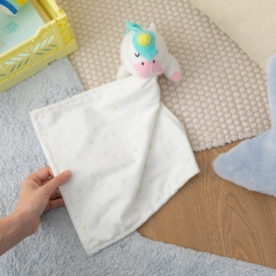 Manta de bebé branca com peluche azul e rosa sobre tapetes texturizados