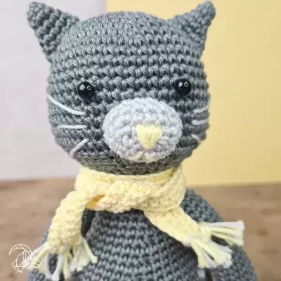 Peluche de gato cinzento de croché com cachecol amarelo claro