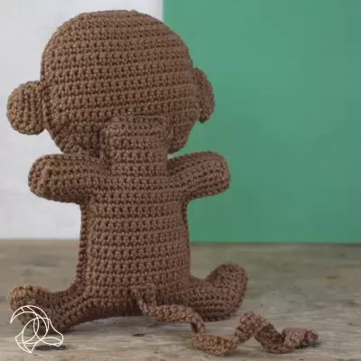 Boneco de macaco em croché castanho sentado