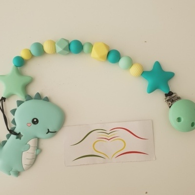 Prendedor de chupeta com contas coloridas e figura de dinossauro verde