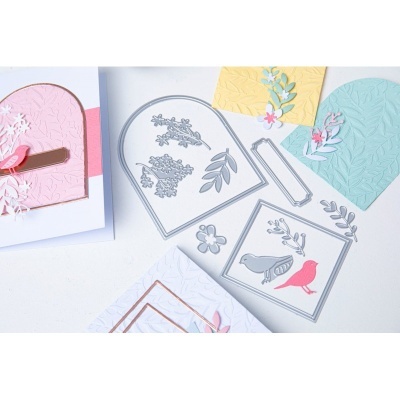 Moldes metálicos com desenhos de natureza sobre papéis texturizados coloridos para artesanato.
