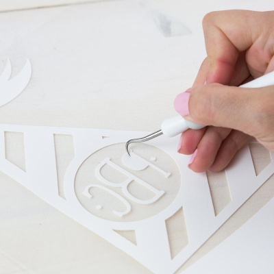 Mão com ferramenta branca a recortar stencil branco com texto DBC