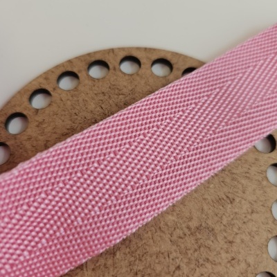 Cinta rosa têxtil com textura sobre base redonda de madeira com buracos