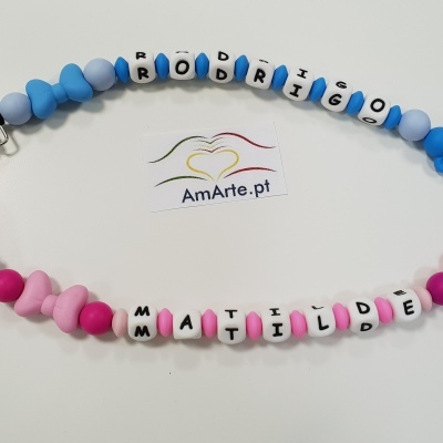 Dois porta-chupetas personalizados em silicone azul e rosa com nomes.