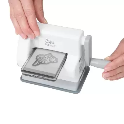 Máquina de cortar formas manual branca e cinza Sizzix SIDEKICK em uso