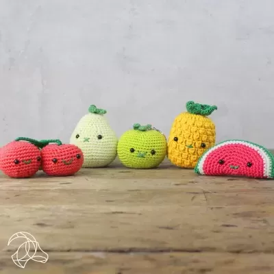 Frutas de crochet coloridas em cima de uma mesa de madeira