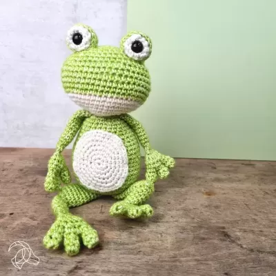 Boneco de rã de crochet verde e branco sentado