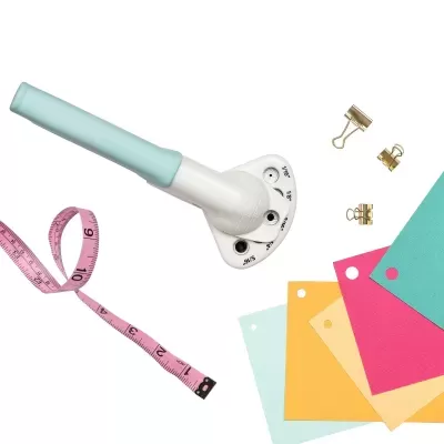 Cortador rotativo branco e azul claro com fita métrica rosa e amostras de cores