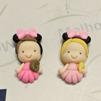 Dois bonecos de borracha cor de rosa com laços e orelhas pretas sobre superfície clara