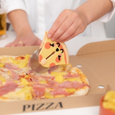 Roda de pizza com cabo decorativo a cortar pizza numa caixa de cartão com a palavra PIZZA