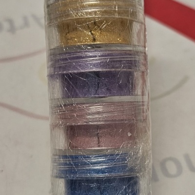 Cinco frascos de pigmentos coloridos empilhados embalados em plástico