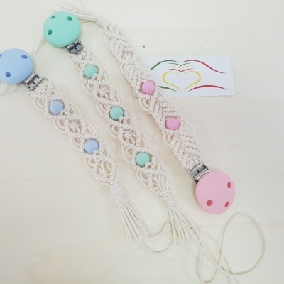Três presilhas para chupeta em macramé com contas coloridas e clips coloridos sobre fundo claro
