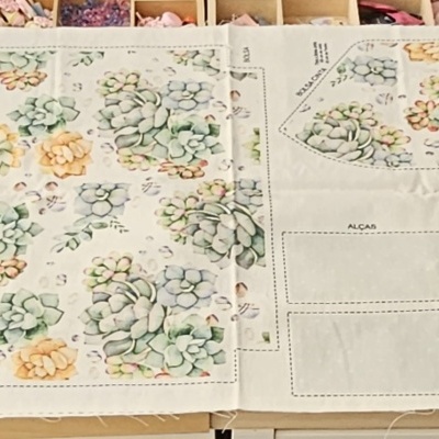 Três toalhas de mesa brancas com estampas florais verdes e amarelas sobre superfície de madeira