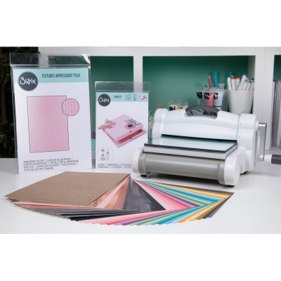 Máquina de corte e estampagem com papéis coloridos e caixas de acessórios Sizzix