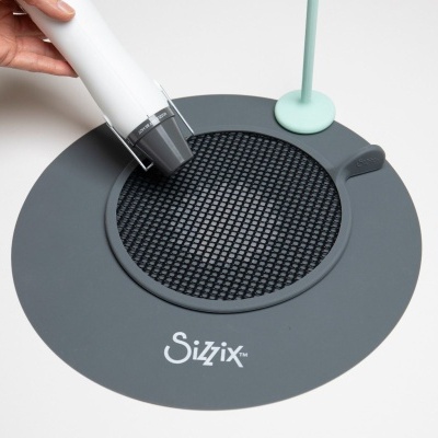 Equipamento Sizzix cinzento com grelha preta e dispositivo branco em mesa branca
