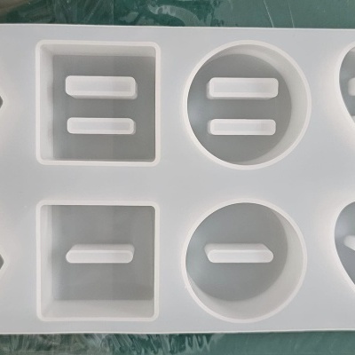 Forma de silicone branca com cavidades em formatos variados, incluindo hexágono, retângulo, círculo e coração.