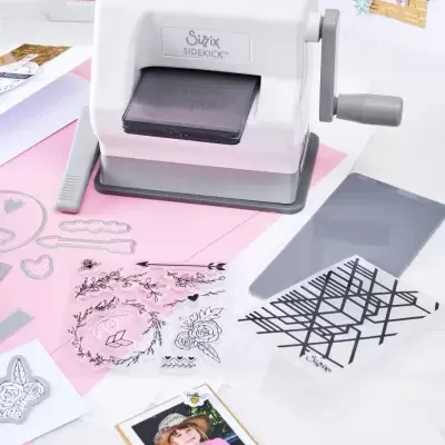 Máquina de cortar Sizzix Sidekick branca e cinzenta com carimbos e cartões decorativos