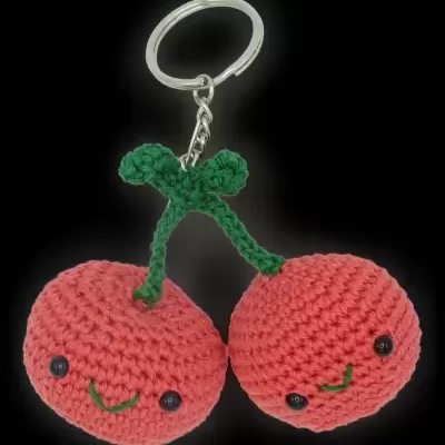 Chaveiro de crochete duas cerejas vermelhas com rostos sorridentes e caule verde