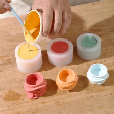 moldes cilíndricos e copos de silicone coloridos com líquido sendo vertido