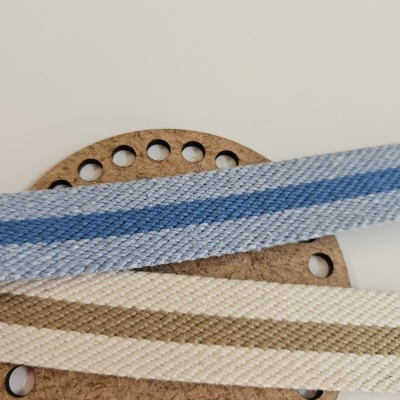Cabos de tecido listrados azul e bege sobre base de cortiça com furos