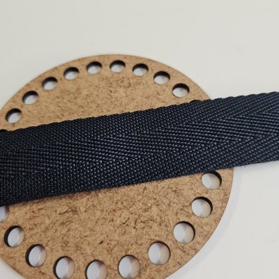 Círculo de cortiça com furos e fita preta texturizada deitada em cima, fundo branco.