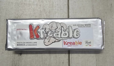 Barra de pasta para modelar branca em embalagem prateada com texto e logótipos