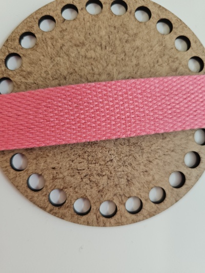 Disco castanho com buracos e fita rosa de tecido em fundo branco