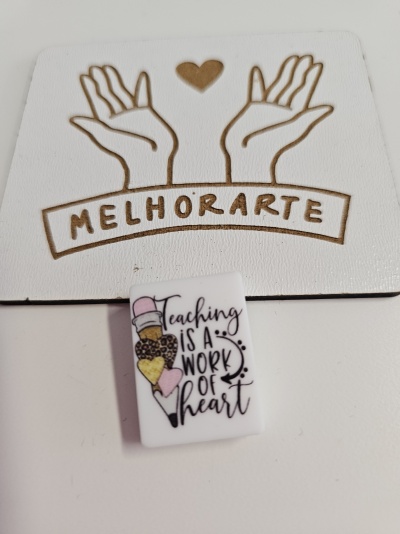 Material com desenho de mãos e texto MELHORARTE e objeto branco com frase Teaching is a work of heart