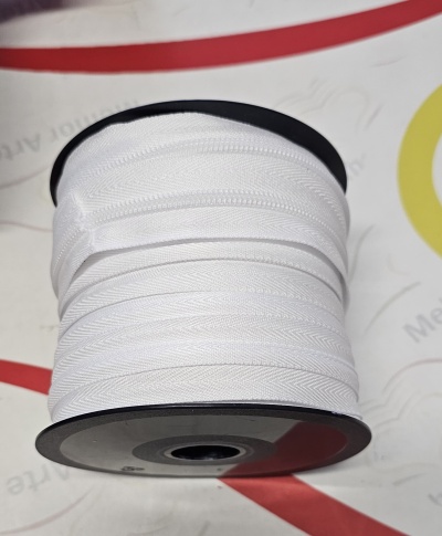 Rolo de fita branca em carretel preto sobre superfície branca com gráficos coloridos