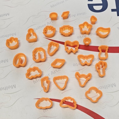 Conjunto de cortadores de massa/laranja com vários formatos sobre superfície branca com texto.