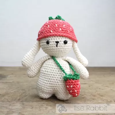 Boneco de crochê com chapéu e bolsa em forma de morango