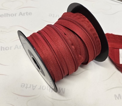 Rolo de viés vermelho em carretel preto sobre superfície com texto 'Melhor Arte'