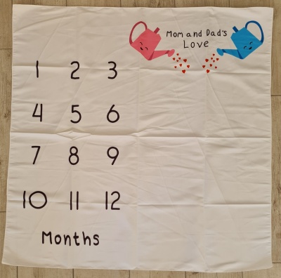 Manta branca com números e ilustrações de regadores coloridos e texto em inglês.