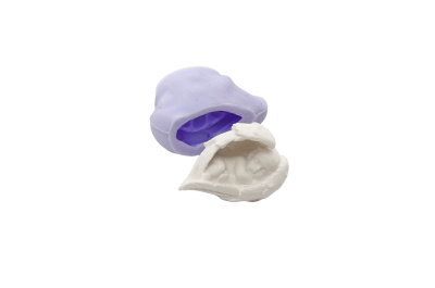 Molde de silicone roxo com escultura branca de bebé dormindo entre mãos.