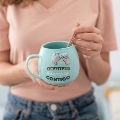 Caneca azul com texto e ilustração, pessoa a segurá-la