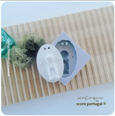 Molde em silicone e figura branca de menino rezando sobre madeira com planta e saco azul