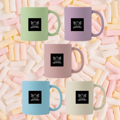 Cinco canecas coloridas com logótipo MELHORARTE sobre fundo de doces marshmallows.