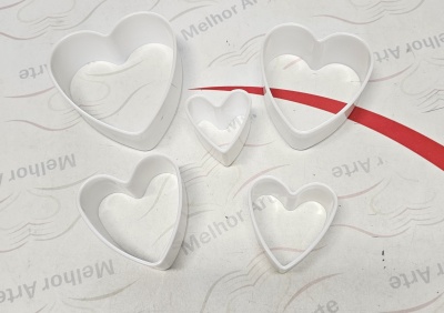 Conjunto de cortadores de massa em forma de coração brancos sobre fundo branco com texto e linha vermelha