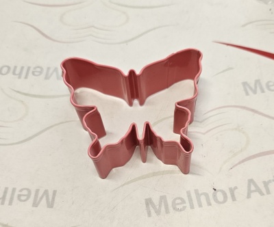 Forma de metal rosa em forma de borboleta sobre superfície clara com texto parcial