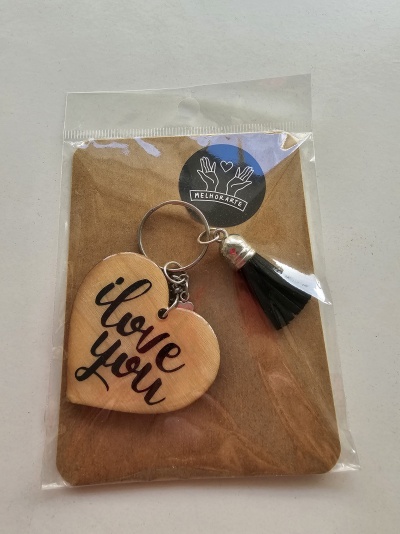 Porta-chaves de coração em madeira clara com texto e tassel preto na embalagem