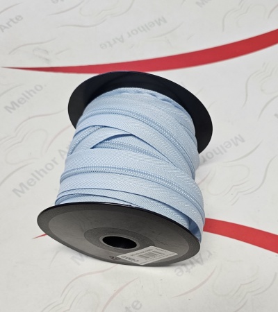 Rolo de fita azul claro enrolada num carretel preto sobre superfície branca com faixas vermelhas