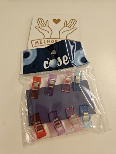 Pacote com presilhas coloridas de mola e cartão com desenho de mãos e coração