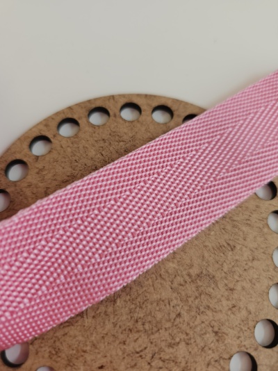 Cinta rosa têxtil com textura sobre base redonda de madeira com buracos