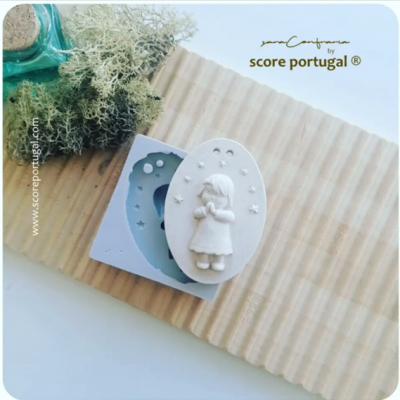 Molde de silicone azul claro e peça decorativa branca com figura de menina ajoelhada sobre madeira rústica