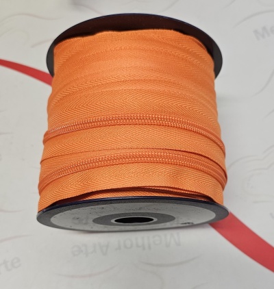 Rolo de fecho zipper laranja em carretel preto sobre superfície branca com texto