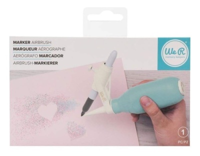 Aerógrafo marcador We R memory keepers azul e branco em uso sobre papel rosa