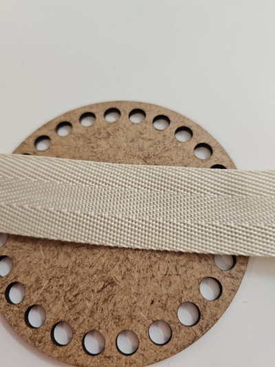 Fita têxtil creme sobre peça circular de madeira com furos