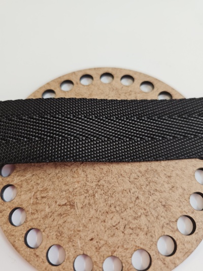 Tira preta de tecido sobre disco redondo de madeira com furos