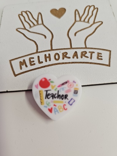 Broche em forma de coração branco com ilustrações e texto Teacher sobre fundo branco com desenho e texto MELHORARTE